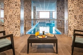 una mesa con un plato de frutas y bebidas frente a una piscina