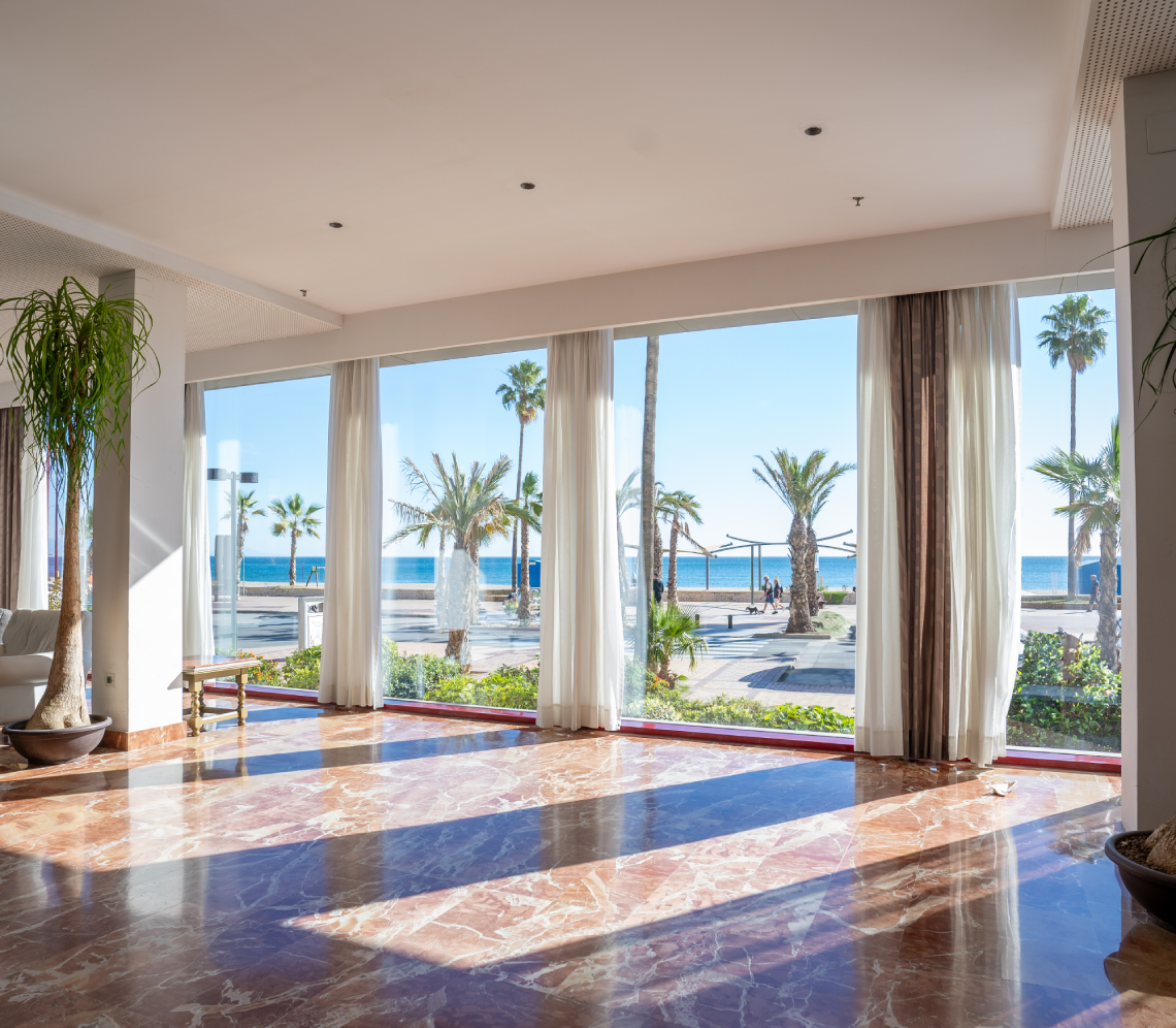 a room with a view of the ocean and palm trees