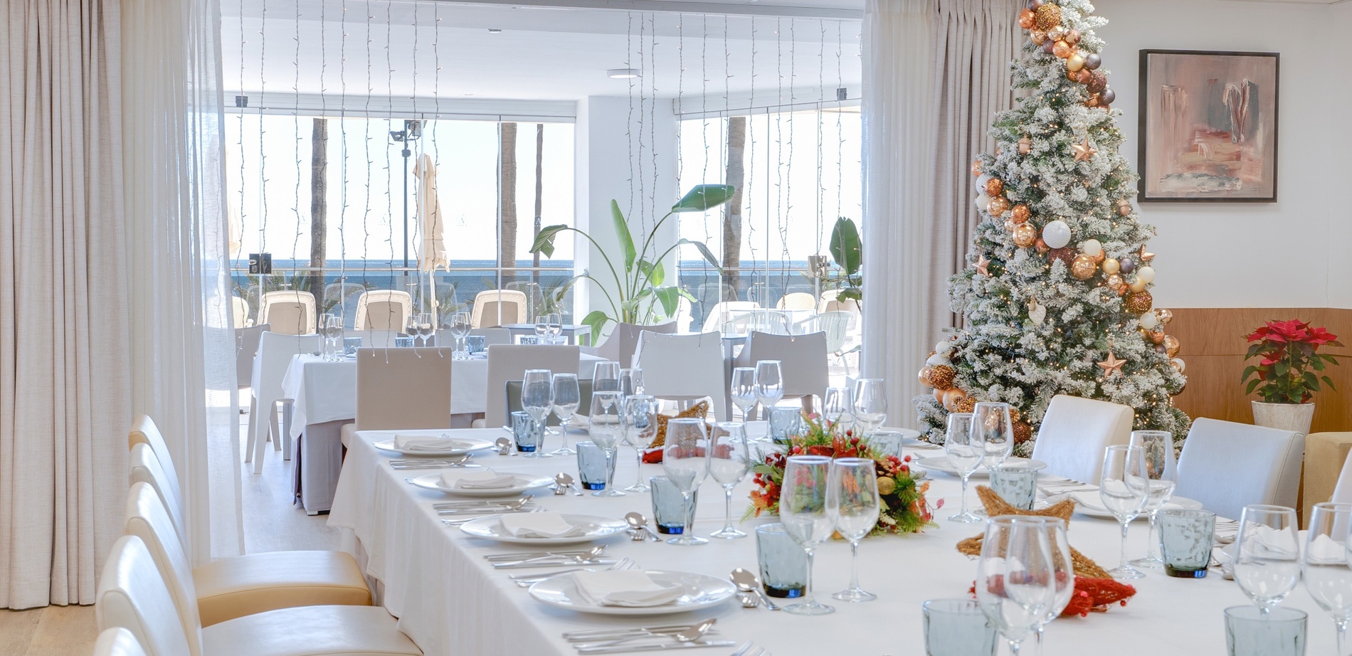 una mesa larga con copas de vino y un árbol de navidad