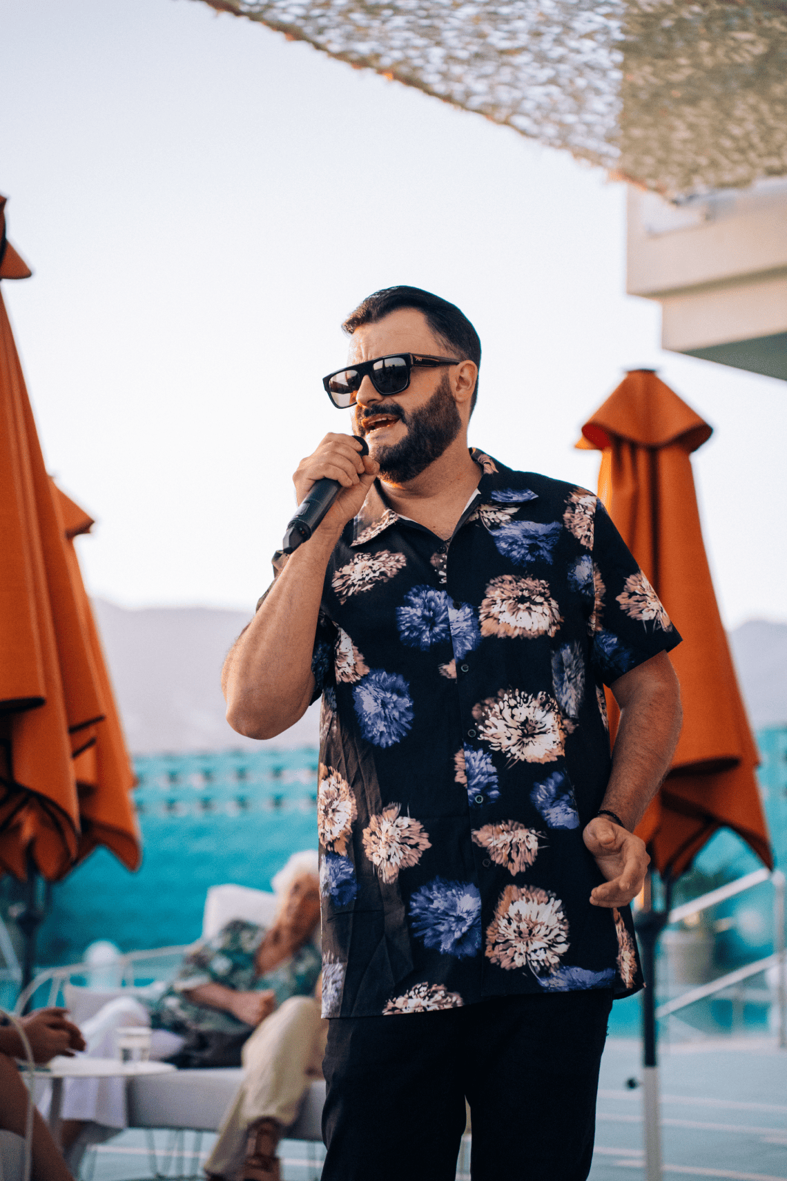 un homme avec une barbe et des lunettes de soleil chante dans un microphone