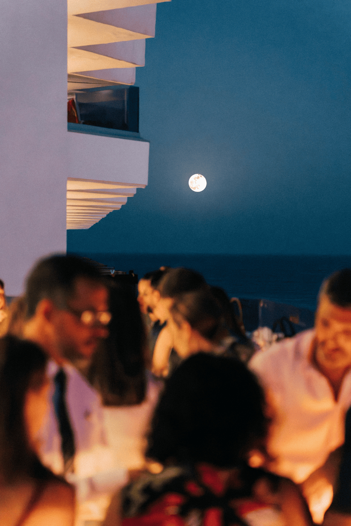 une pleine lune se lève au-dessus d' un groupe de personnes