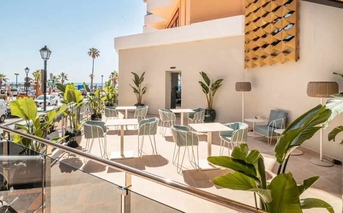 Terrasse extérieure de l'Hôtel Angela avec tables et chaises.