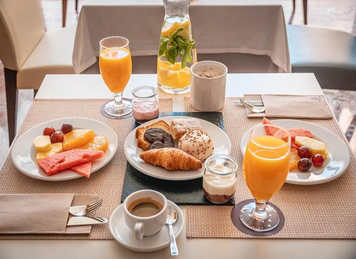 Petit déjeuner Angela Hotel : fruits frais, viennoiseries, café et jus d'orange.