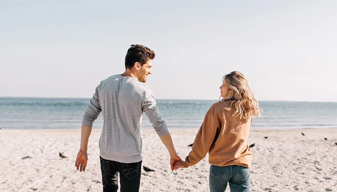 Young couple at the beach, Angela and her boyfriend, looking at the sea.