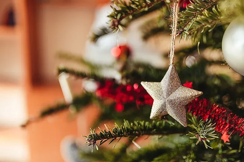 Ornement étoile d'Angela sur sapin de Noël, ambiance festive.