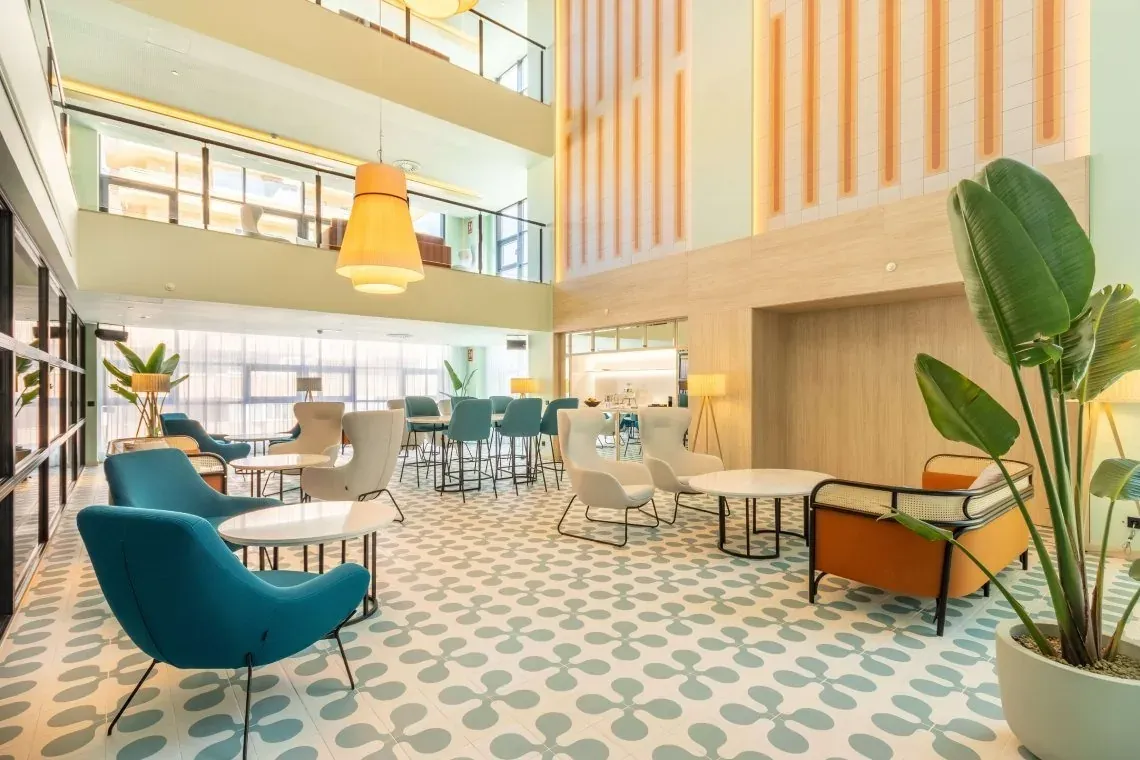 Lobby de hotel Angela: asientos modernos, decoración tropical y luz natural.