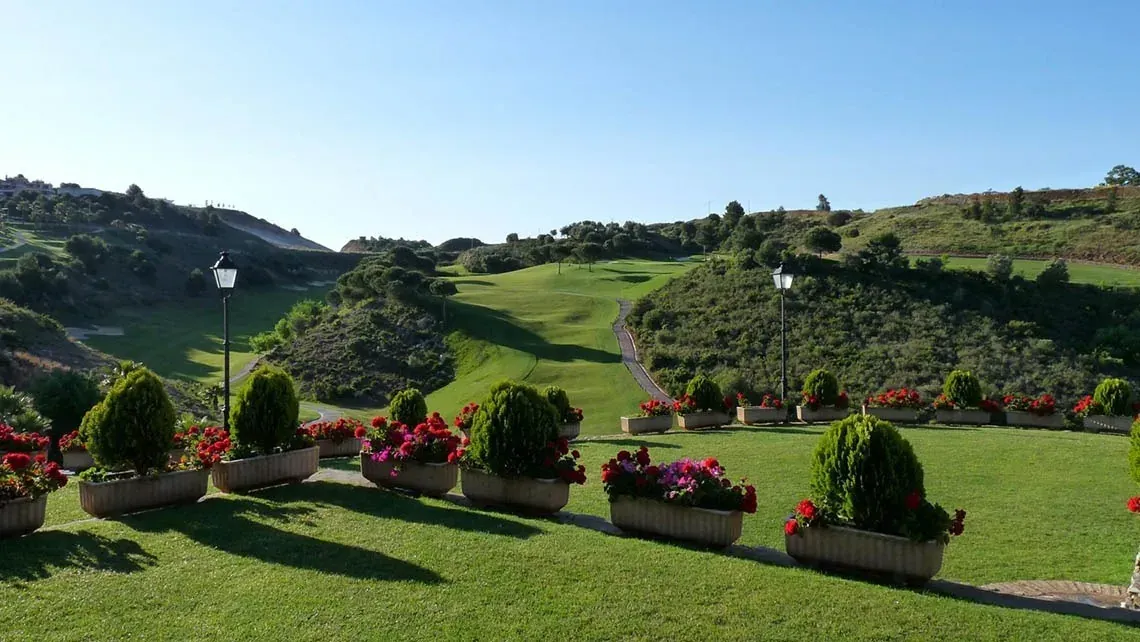 Vistas al campo de golf Angela, con macetas de flores y farolas.