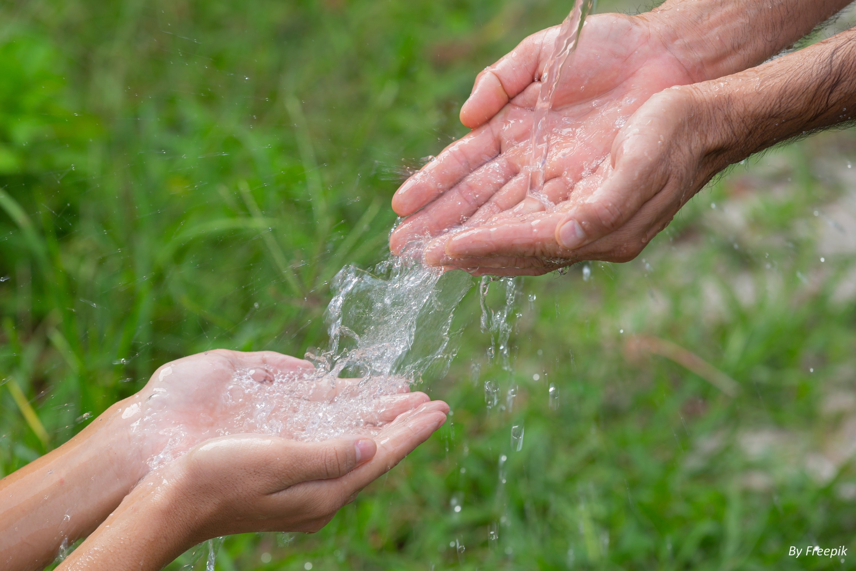 un homme verse de l' eau sur les mains d' un enfant