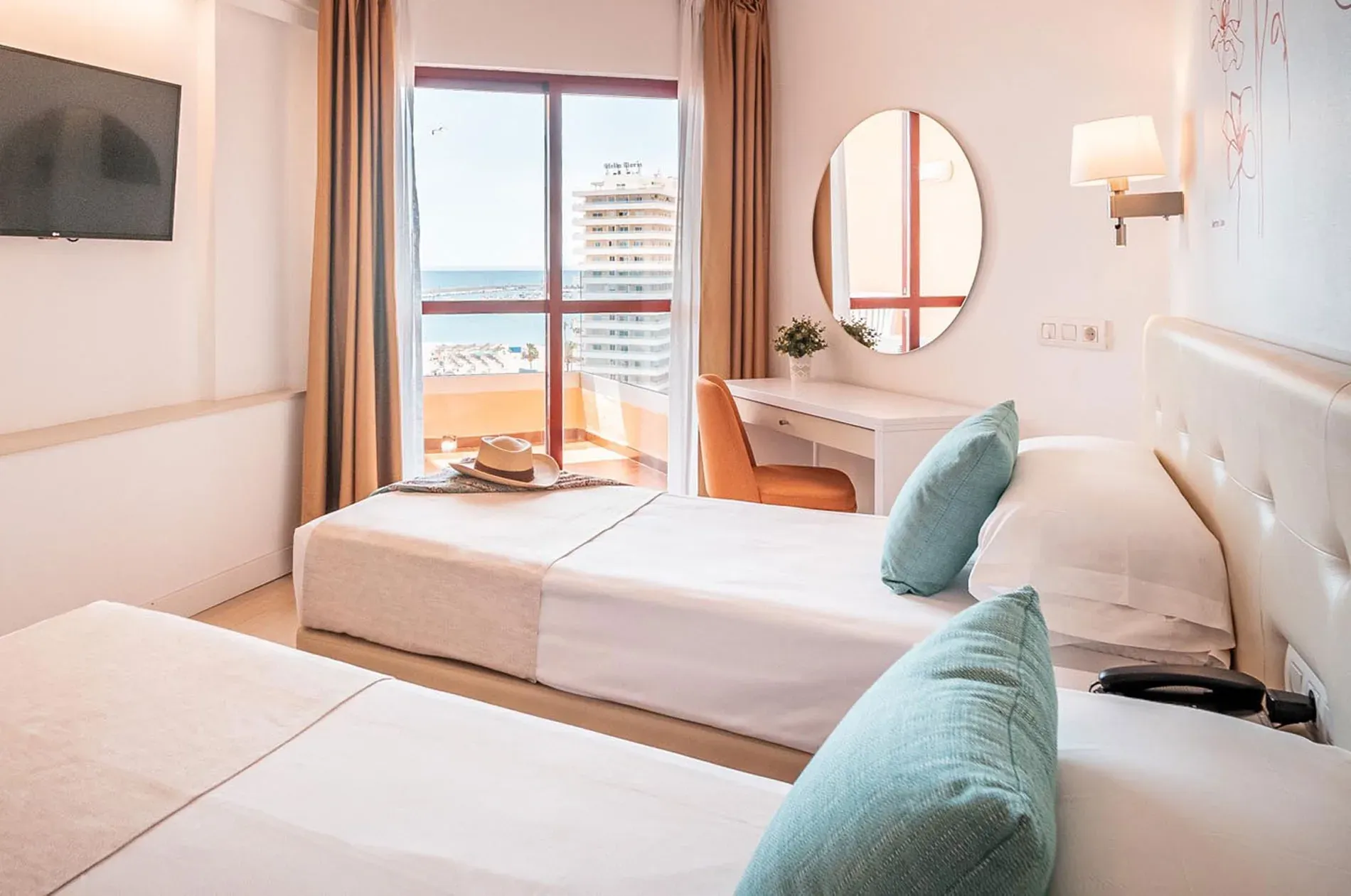 Chambre d'hôtel avec deux lits, balcon et vue sur mer. Le style Angela offre le confort.