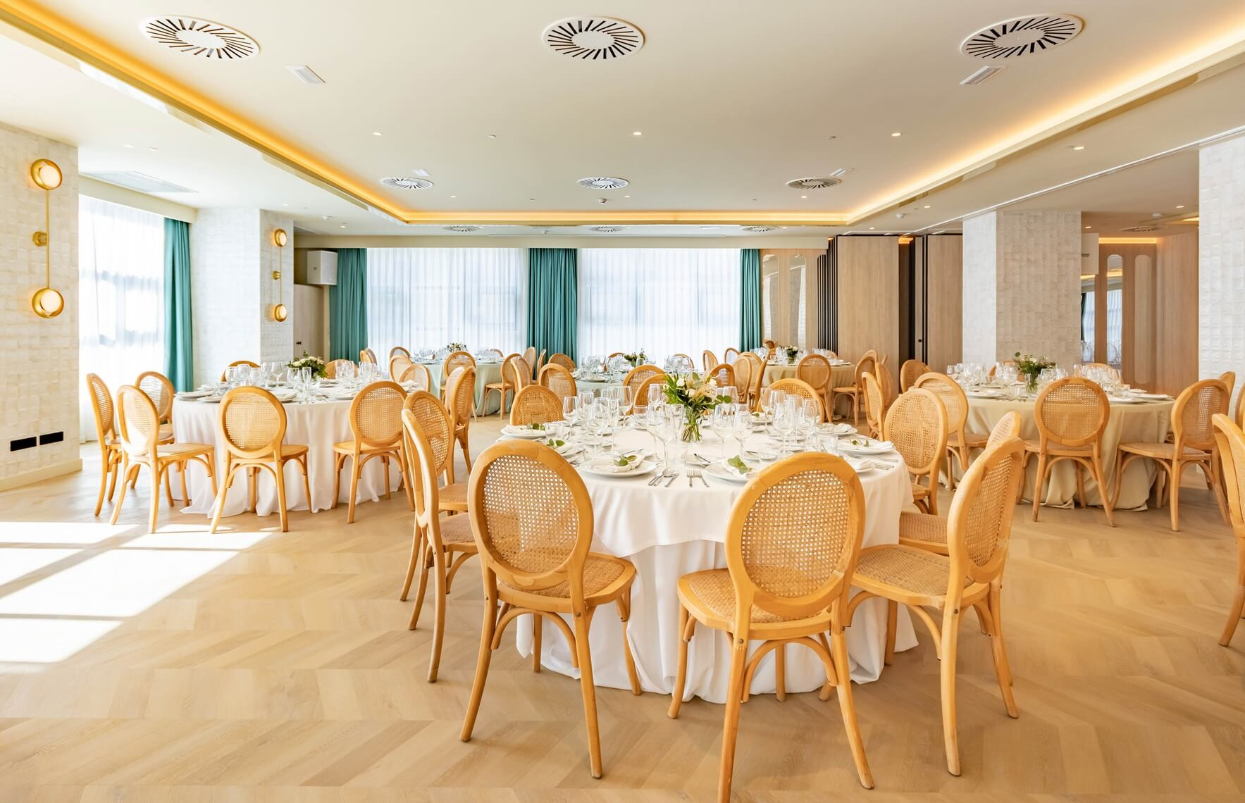 Salón de eventos Hotel Angela on mesas redondas decoradas y sillas de ratán,.