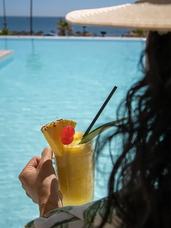 Angela savoure un cocktail tropical au bord de la piscine, parfait pour des vacances.