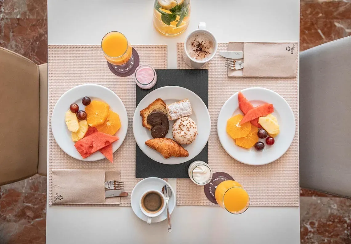 Petit-déjeuner à l'Hotel Angela : fruits frais, viennoiseries et jus.