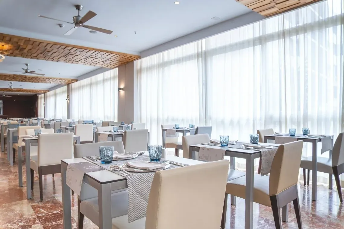 Salle à manger lumineuse à l'hôtel Angela, tables dressées et design moderne.