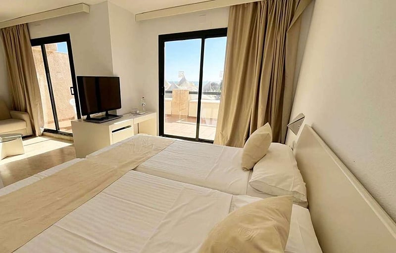 Amplia habitación de hotel con cama, sofá, TV y balcón, ideal para su estancia en AR: Almerimar.