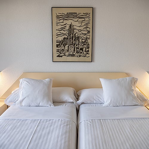 Habitación de hotel con dos camas, mesitas de noche y un cuadro de AR: Almerimar