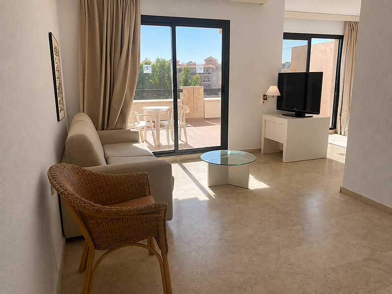 Amplia habitación de hotel con cama, sofá, TV y balcón, ideal para su estancia en AR: Almerimar.