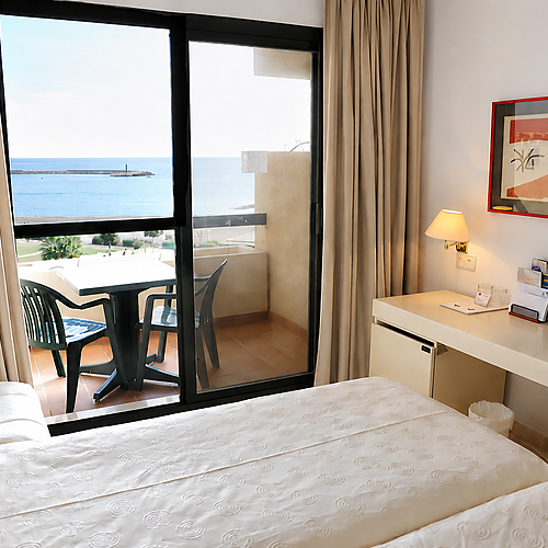 Habitación de hotel en Almerimar con vistas al mar y balcón con fruta fresca.