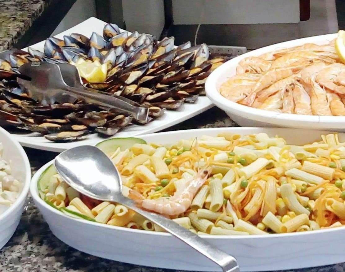 a buffet table with a variety of food including pasta shrimp and mussels