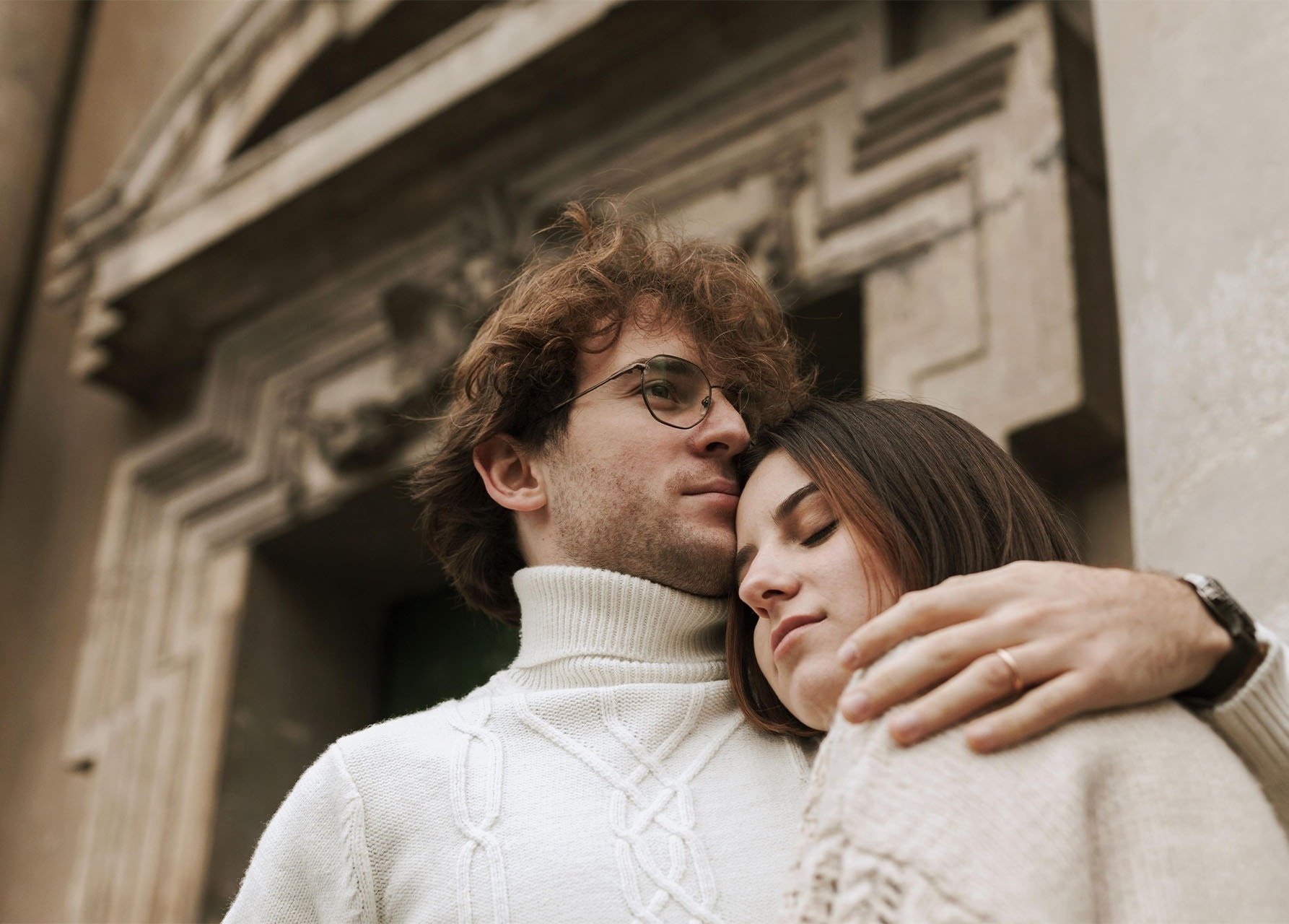 a man and a woman are hugging each other in front of a building