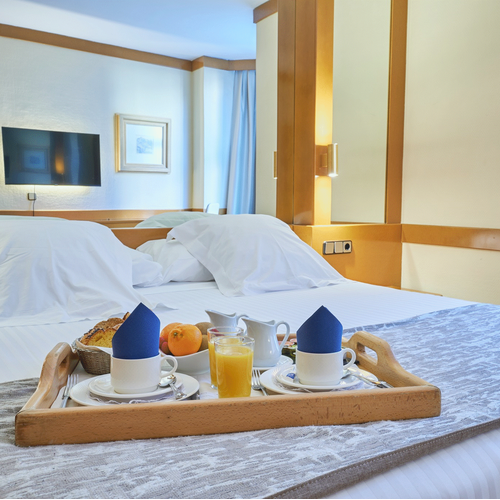 a hotel room with a tray of food on the bed