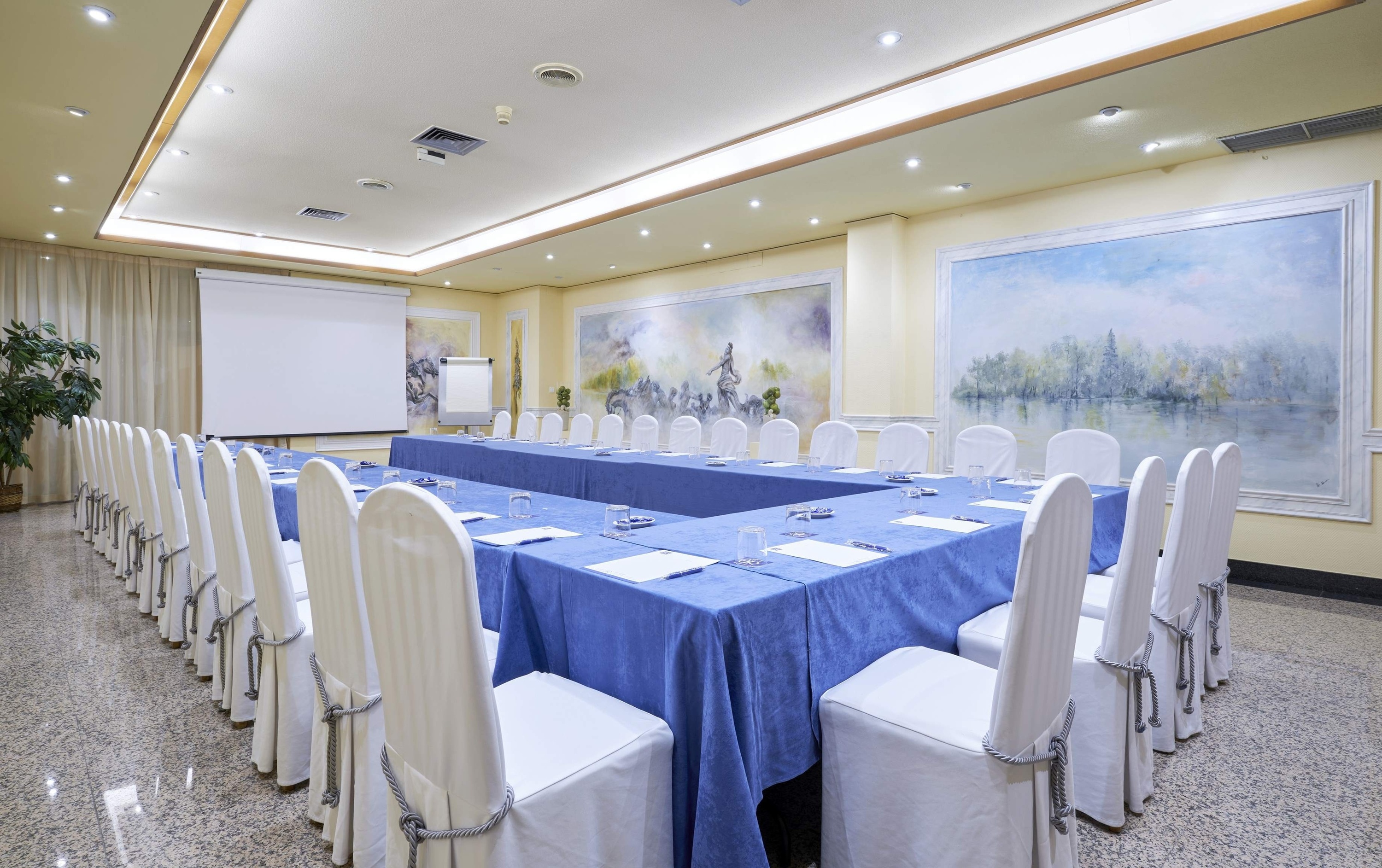 a conference room with tables and chairs and a projector screen
