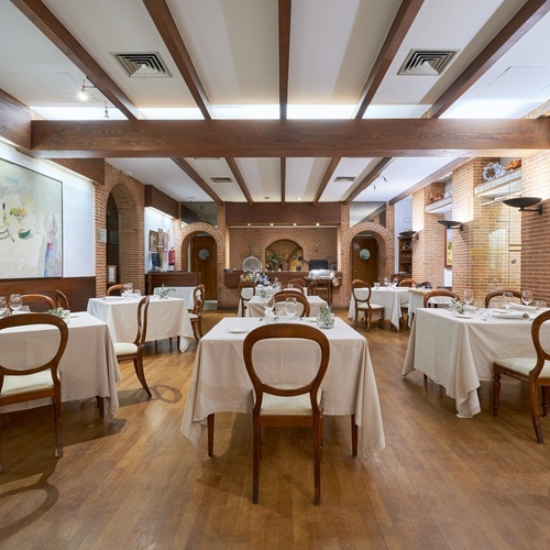 a dining room with tables and chairs and a painting on the wall