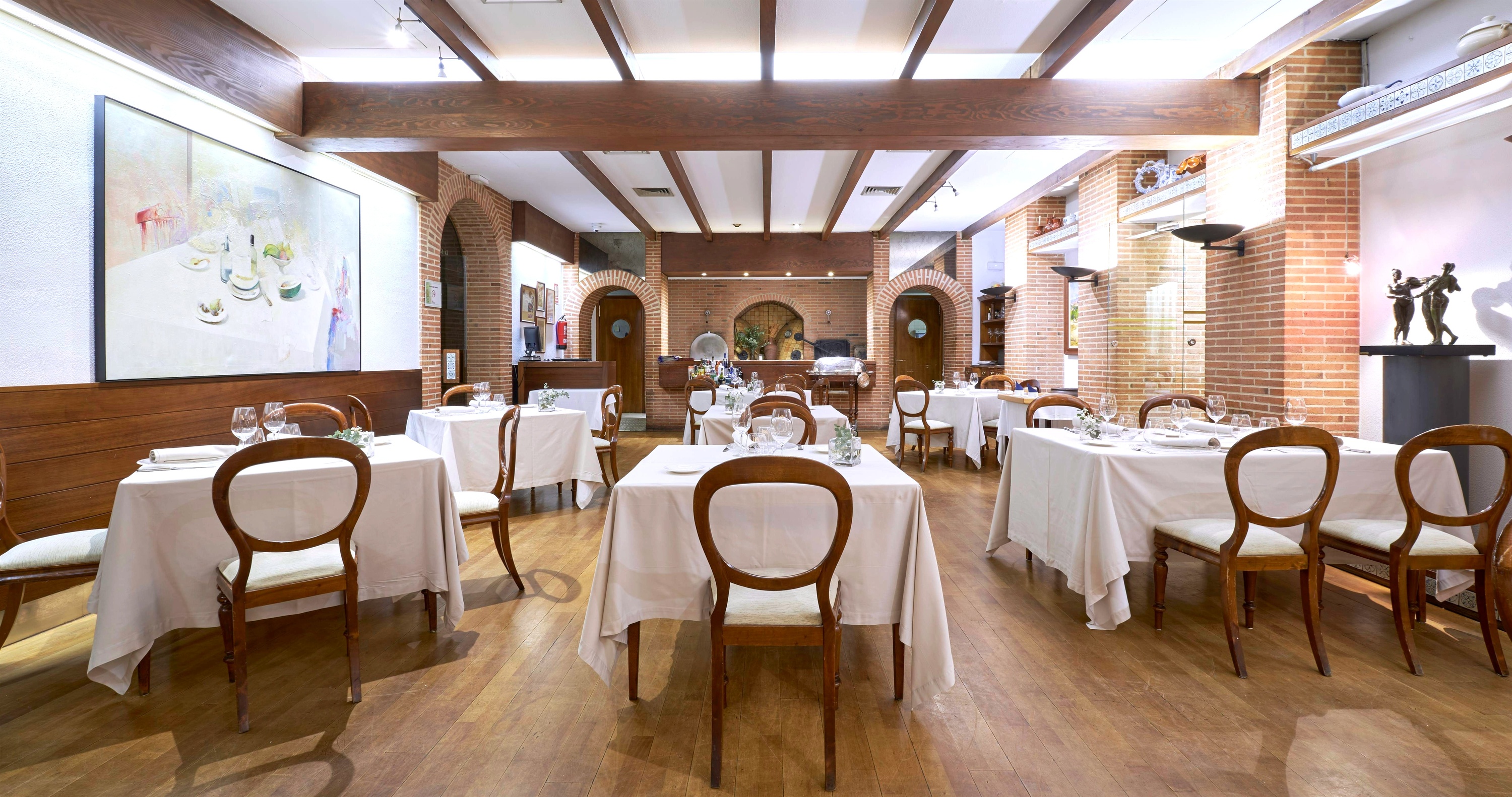 a dining room with tables and chairs and a painting on the wall