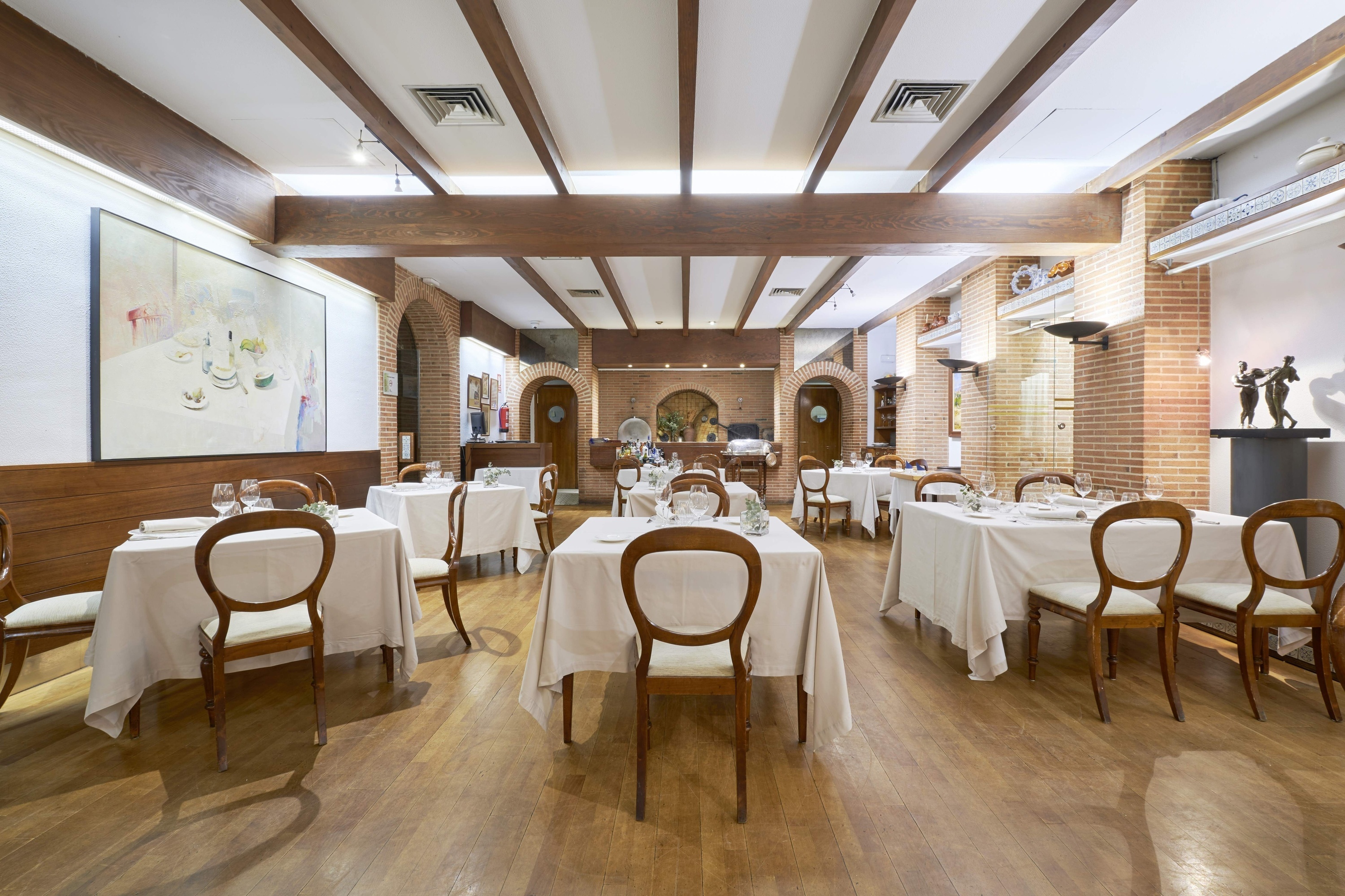 a dining room with tables and chairs and a painting on the wall