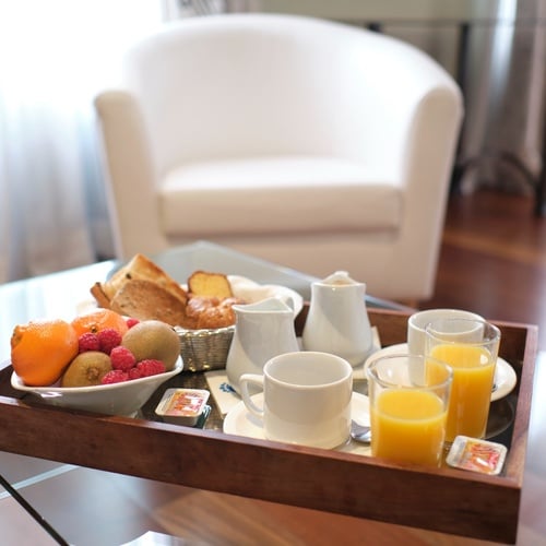 a tray with a bowl of fruit and orange juice on it