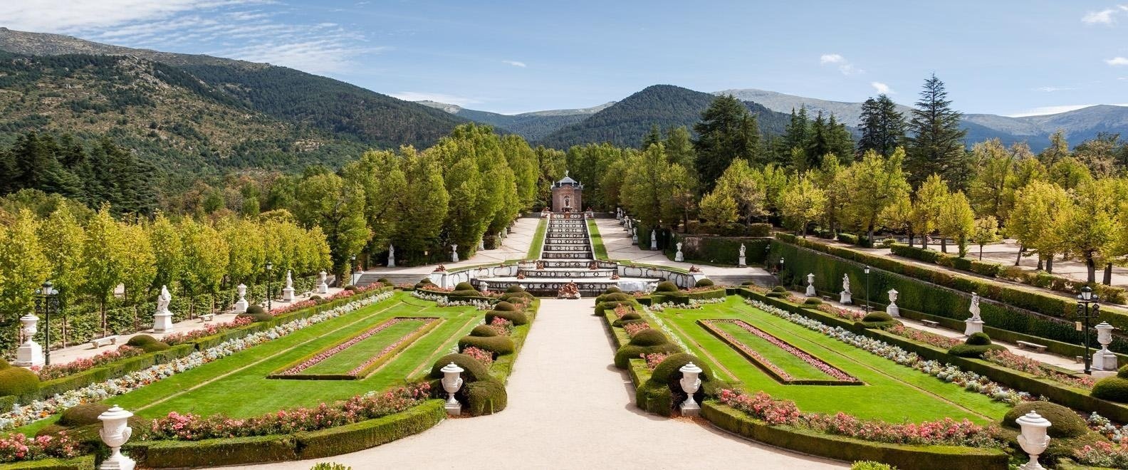 un parque lleno de flores y árboles con montañas en el fondo