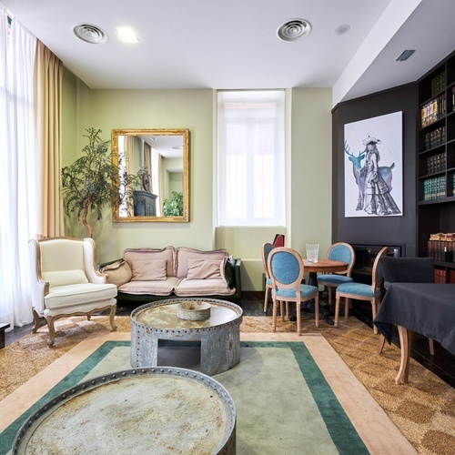 a living room with a couch and chairs and a painting on the wall