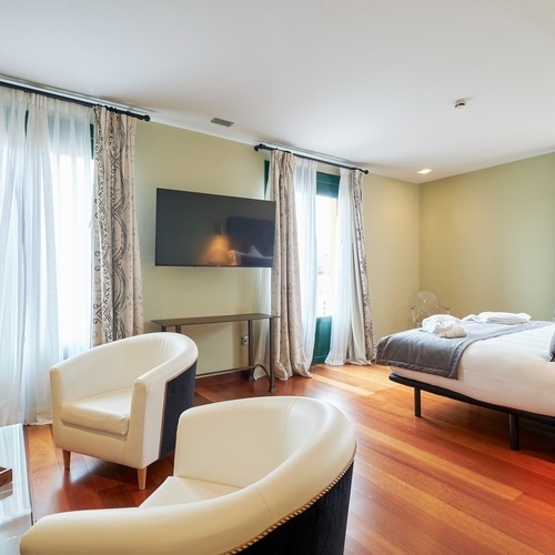 a hotel room with two chairs and a flat screen tv