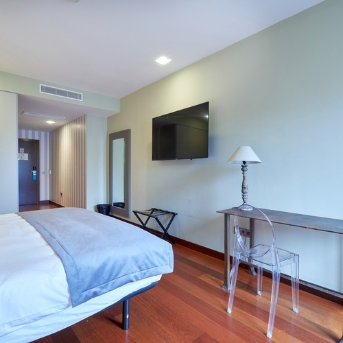 a hotel room with a bed a desk and a flat screen tv