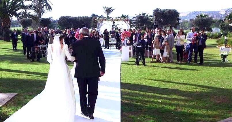 una novia sostiene un ramo de flores mientras se sienta junto a un novio