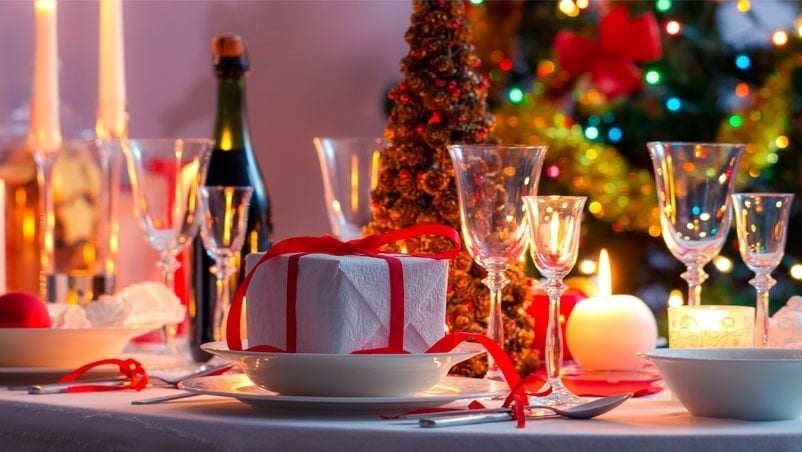 una mesa está decorada para una cena de navidad con un árbol de navidad en el fondo