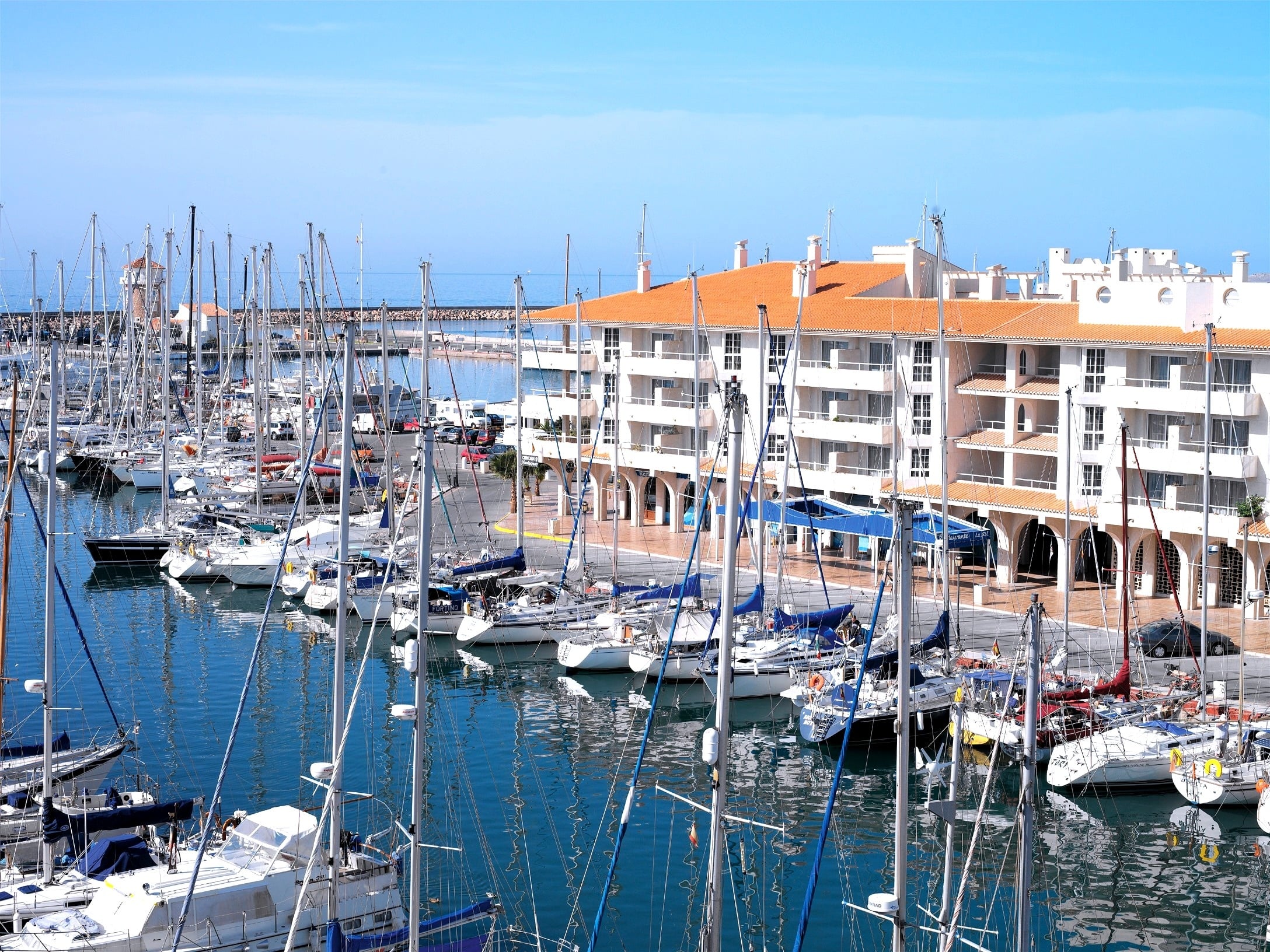 muchos barcos están amarrados en un puerto con un edificio en el fondo