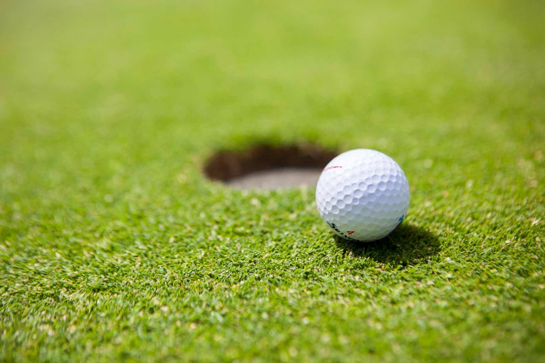 una pelota de golf se sienta en la hierba cerca de un agujero