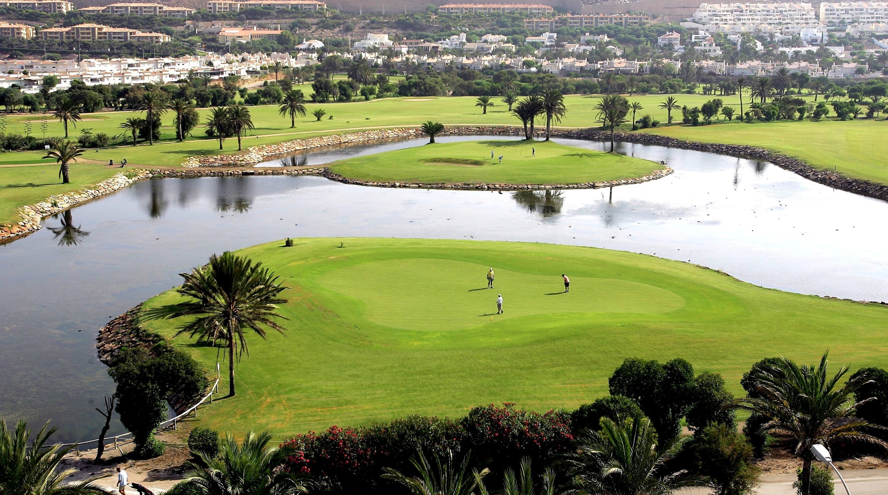 un grupo de personas están jugando al golf en un campo de golf rodeado de agua