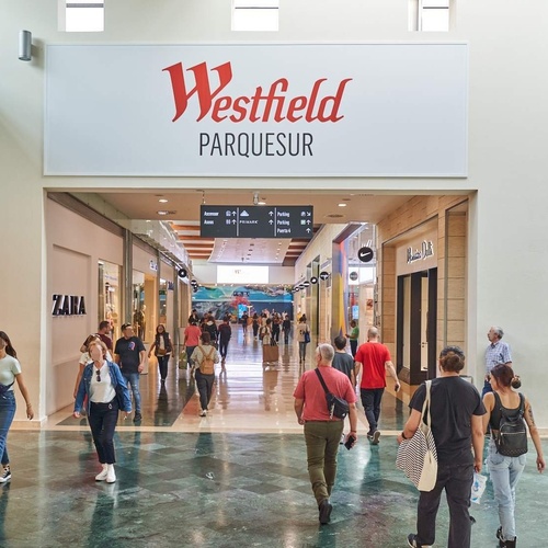 un centro comercial lleno de gente y una tienda de zapatos