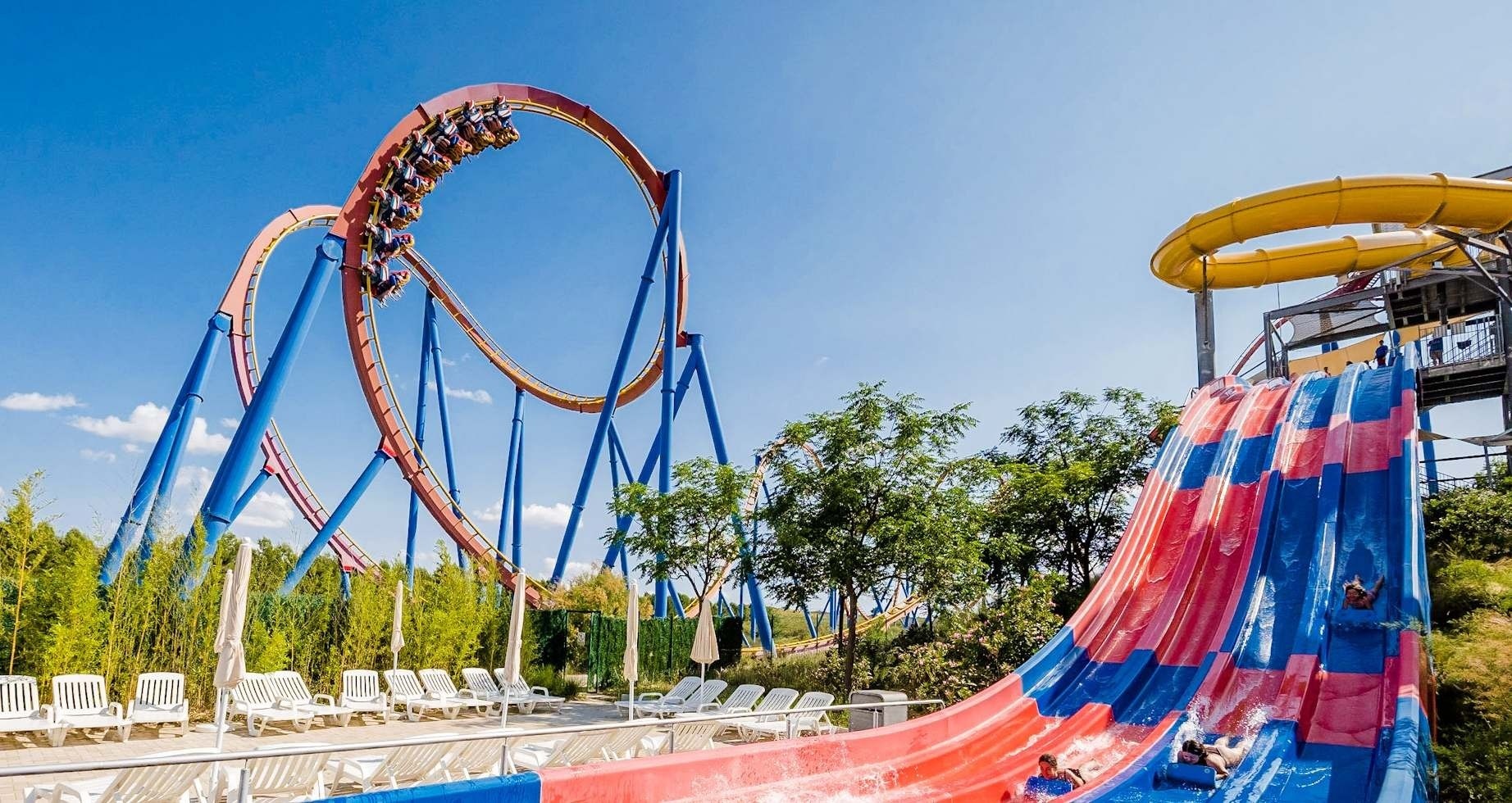 un parque de diversiones con una montaña rusa en el fondo