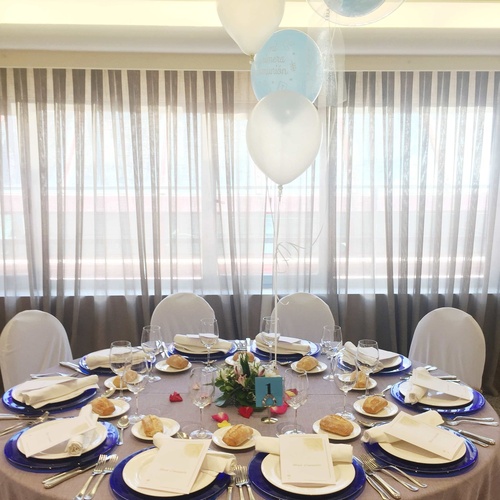 a table with plates and utensils and balloons hanging from the ceiling