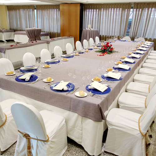 una mesa larga con platos azules y sillas blancas