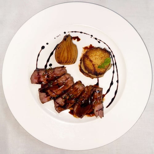 Gourmet steak dish with roasted pear and potato cake, presented at AR: Parquesur.