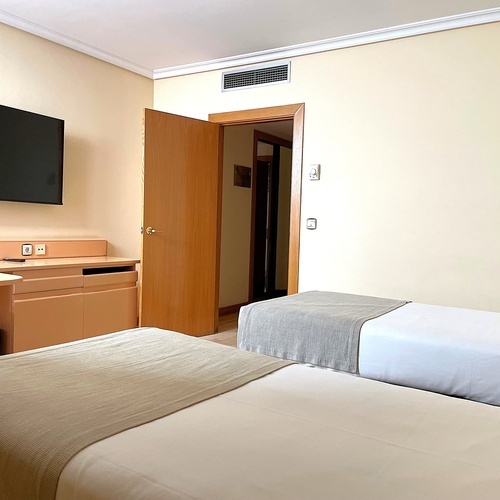 Habitación de hotel doble y moderna con dos camas individuales y TV, ideal para su estancia cerca de AR: Parquesur.