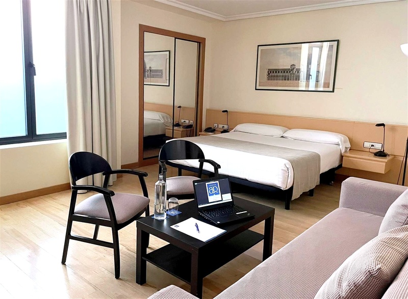Modern studio hotel room near AR: Parquesur with comfortable bed, sofa, and light wood floors.