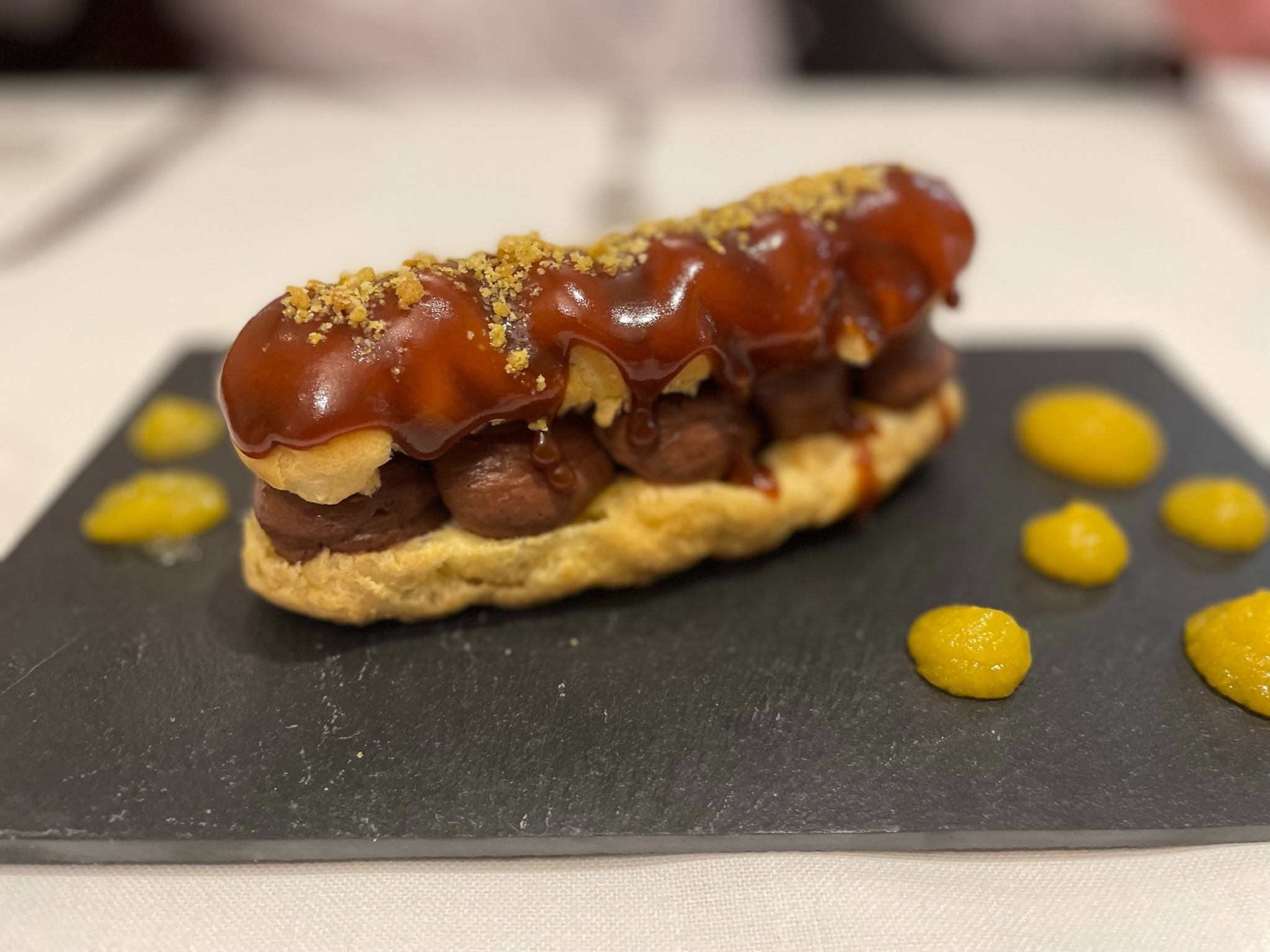 a pastry on a black plate with yellow sauce