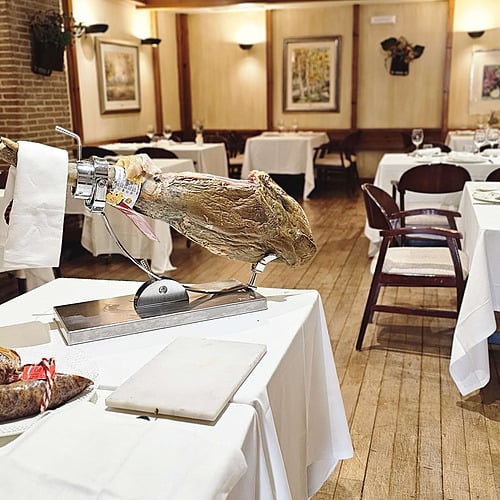 Elegant dining room at AR: Parquesur hotel, featuring set tables, wooden beams, and warm ambiance.