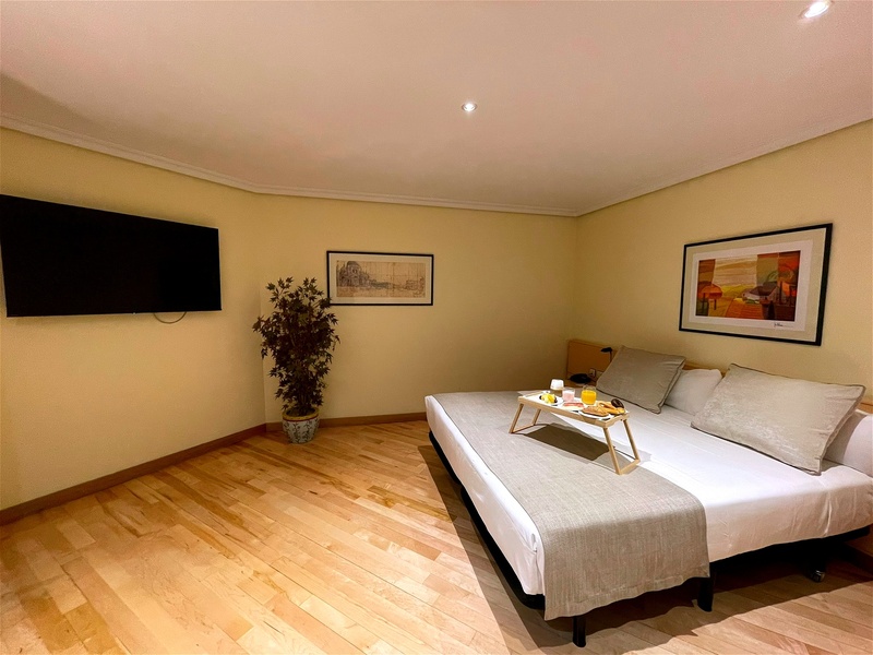 Modern studio hotel room near AR: Parquesur with comfortable bed, sofa, and light wood floors.
