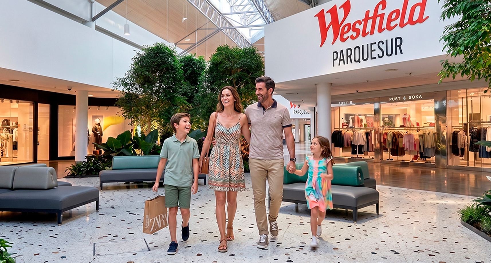 Centro comercial Westfield AR: Parquesur, un interior amplio con palmeras y tiendas.