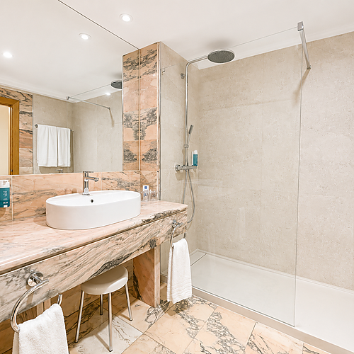 Luxurious AR: Parquesur hotel bathroom featuring marble, vanity with sink, toilet, and a bathtub with shower.